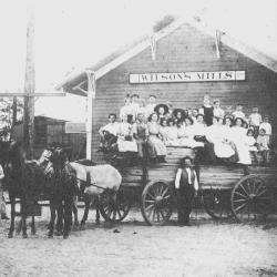 Old train depot with children sitting in large horse-drawn cart