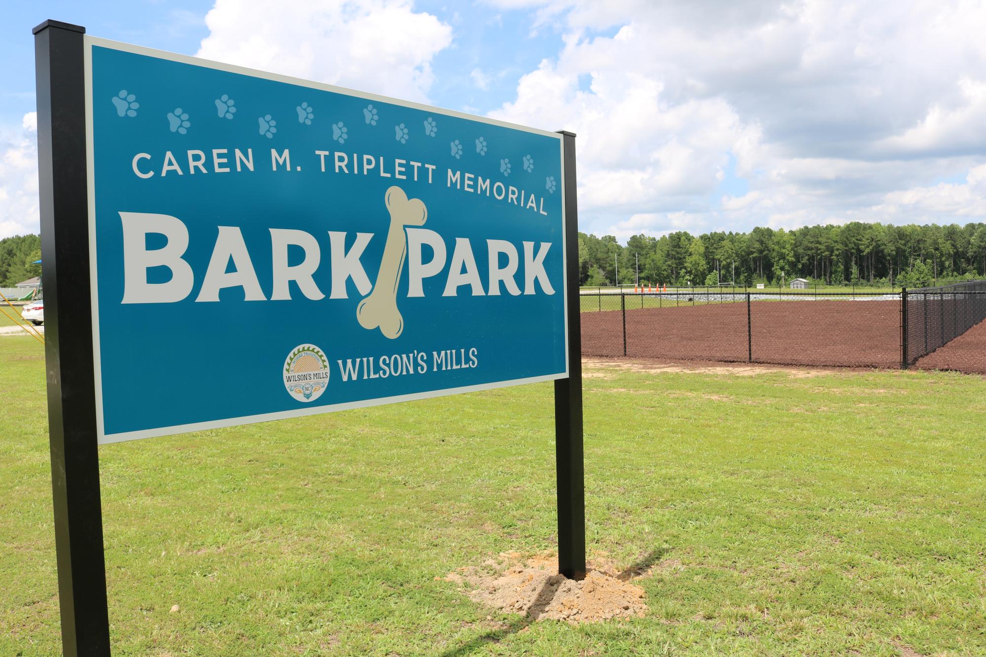 Large blue Bark Park sign with dog park in background